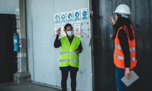 Trabajadores con chalecos reflectantes de seguridad junto a panel de señalización obligatoria de EPIs según RD 485/1997